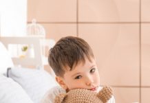Insônia infantil: o que fazer para ajudar seu filho a dormir; Menino triste abraça urso de pelúcia na cama