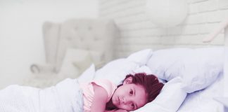 Insônia infantil: quais são as causas e como tratar? Criança deitada na cama com os olhos abertos
