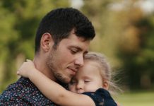 Como a paternidade transforma os homens; Pai abraçando filha pequena no colo