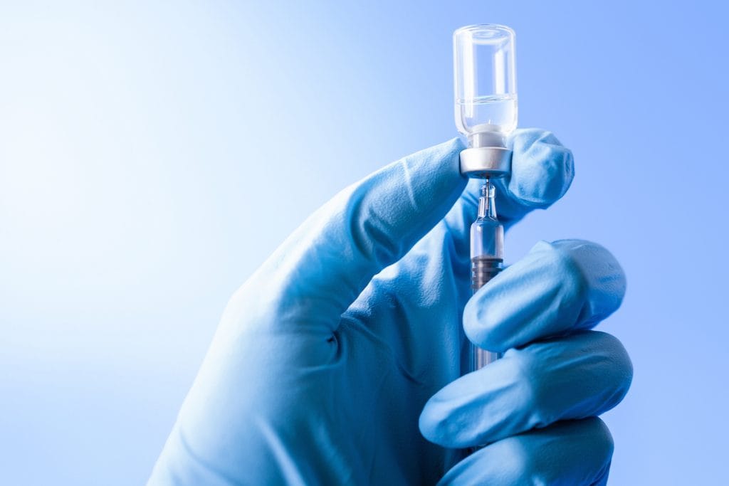 Vacina da Pfizer é segura em crianças entre 5 e 11 anos, dizem fabricantes; Mão de médico com luva azul segura ampola de vacina