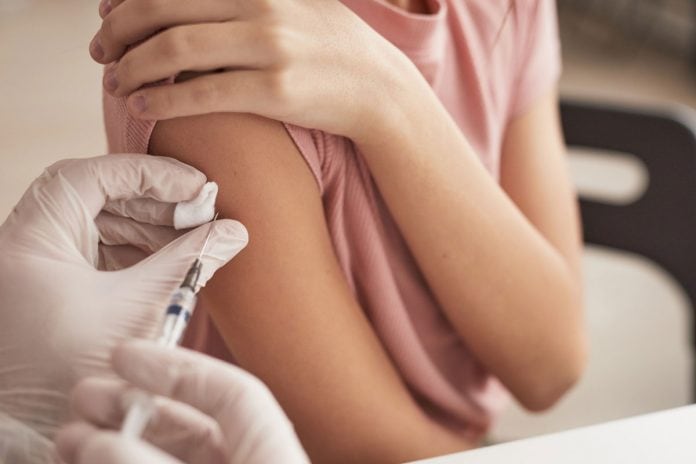 Vacinação de adolescentes: esclarecendo as principais dúvidas dos pais; médico aplicando vacina em adolescente