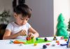 Dicas de atividades para aproveitar o Dia das Crianças em família; criança brincando com massinha na mesa