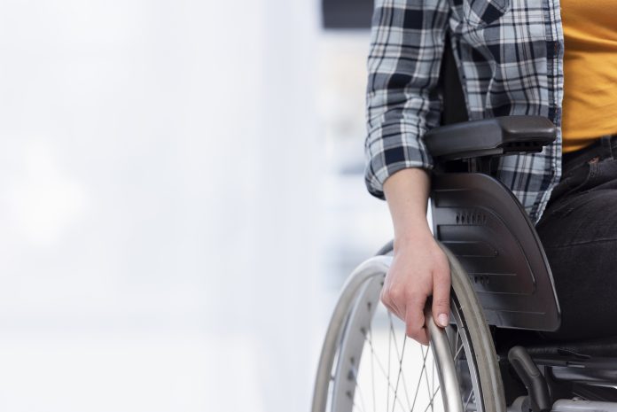 Duchenne: a forma de distrofia muscular mais comum em crianças; criança sentada em cadeira de rodas com a mão em uma das rodas