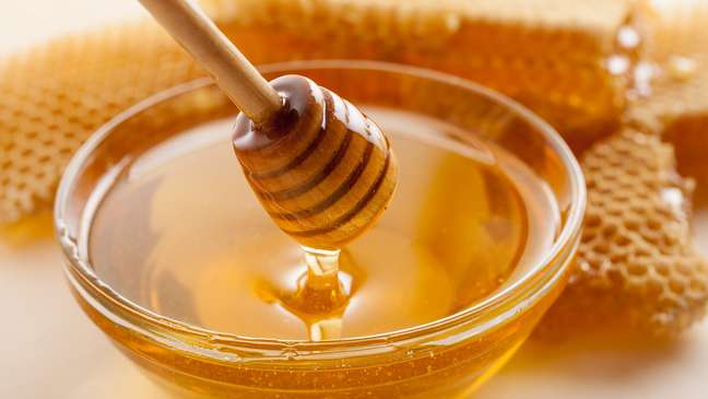 13 alimentos superpoderosos para a saúde das crianças; foto de um pote de mel com pedaços da colmeia atrás