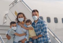 Família com crianças com malas entrando em avião durante a pandemia, todos estão de máscara