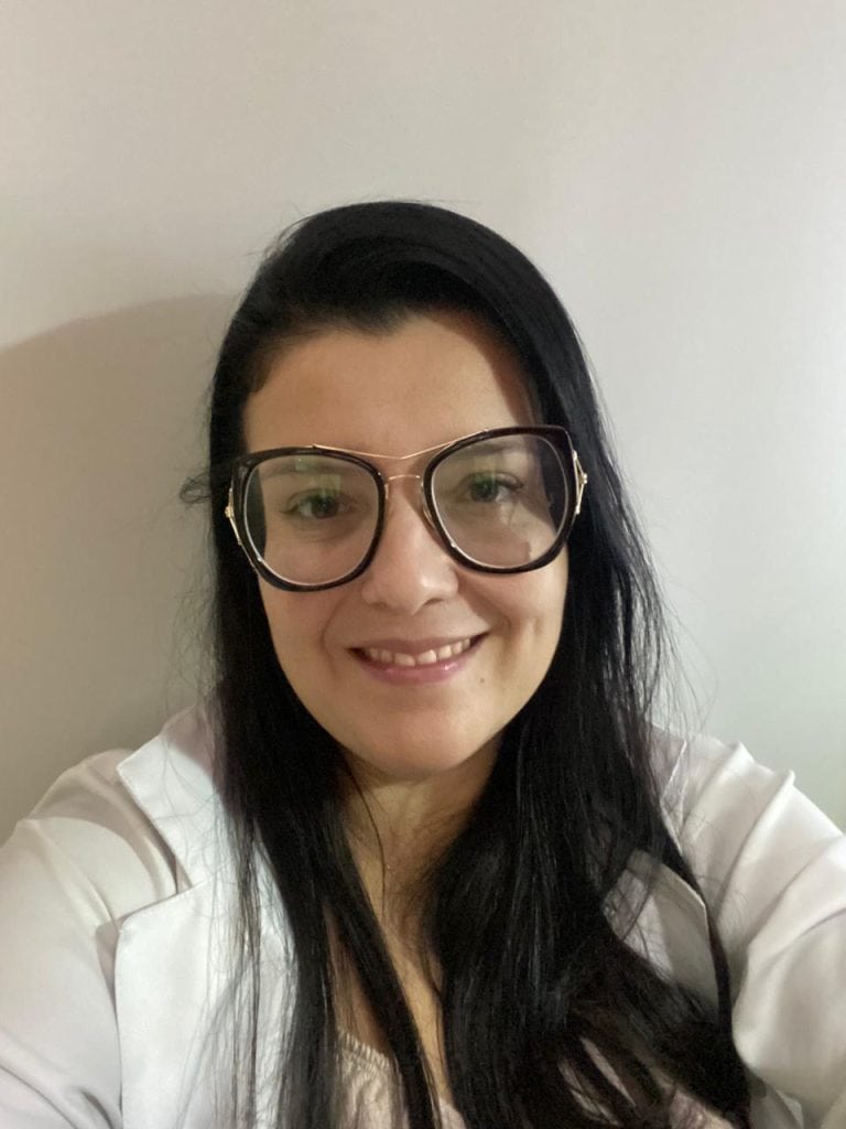 Fonoaudióloga Gabriela Rodrigues, de óculos e jaleco branco