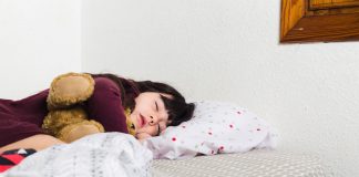 Menina dorme na cama abraçada com ursinho, práticas de higiene de sono ajudam a dormir melhor