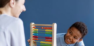 A importância de projetos de lei inclusivos para crianças TDAH; criança sorrindo brincando com brinquedo de contagem colorido com uma mulher de costas sorrindo