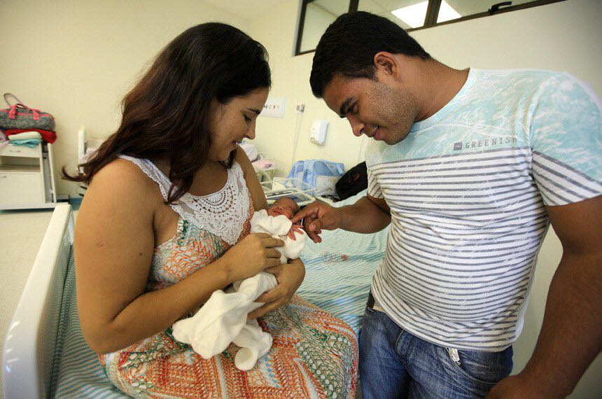 Casal olha para bebê recém-nascido; PEC licença-maternidade
