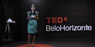 TEDx: como a neurociência pode contribuir para o sucesso das crianças; Liubiana Arantes com vestido verde segurando um cérebro de plástico no TEDx Belo Horizonte