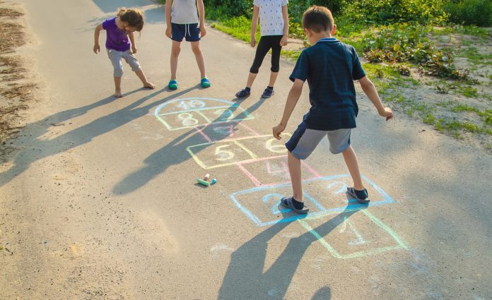 Crianças brincam de amarelinha em piso de asfalto; Movimento discute como tornar ruas mais atrativas para as crianças