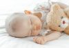 Bebê dorme abracado com ursinho de pelúcia; sono do bebê podem impactar em risco de obesidade