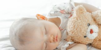 Bebê dorme abracado com ursinho de pelúcia; sono do bebê podem impactar em risco de obesidade