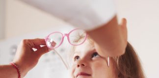 Pessoa colocando óculos em menina com problemas de visão das crianças