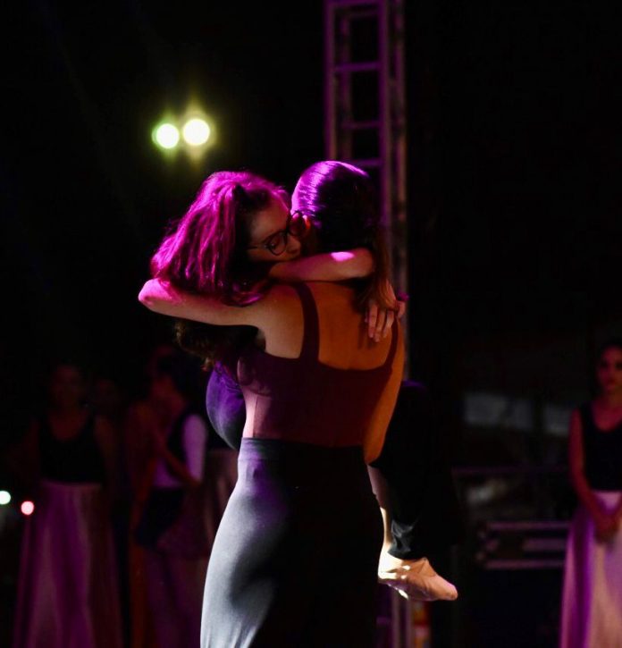 Durante espetáculo de dança, Mônica PItanga segura a filha Luisa com os braços