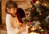 Menina séria mexe em árvore de Natal; Festas de fim de ano podem ser difíceis para as crianças