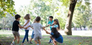 Crianças de mãos dadas formam círuclo em parque ao ar livre