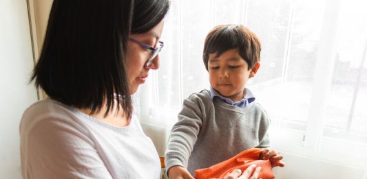 Mãe e filho realizando o reuso de material escolar para o ano letivo, evitando desperdícios