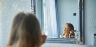Criança sentada em frente ao espelho observando seu reflexo