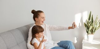 No sofá, mãe tira foto sua com a filha ppelo celular