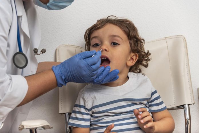 Profissional de saúde aplica cotonete no nariz de criança para teste de Covid