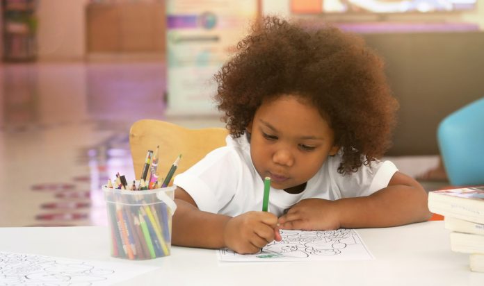 Menina de cabelo crespo pinta desenho em papel
