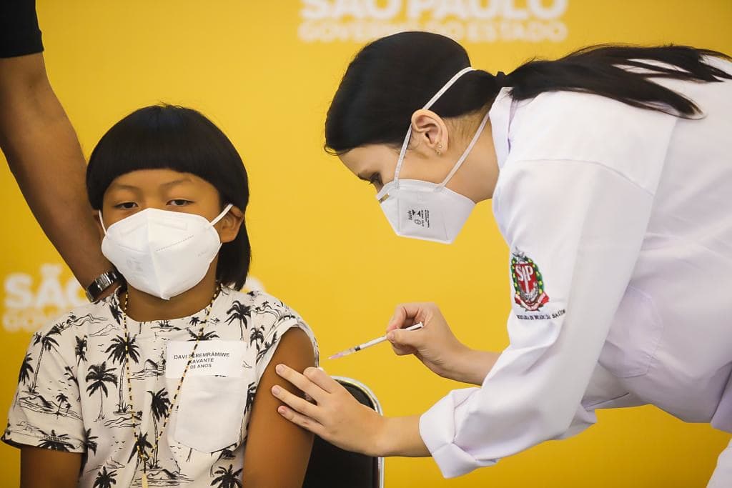 Menino indígena recebendo a primeira dose da vacina da Pfizer contra covid-19