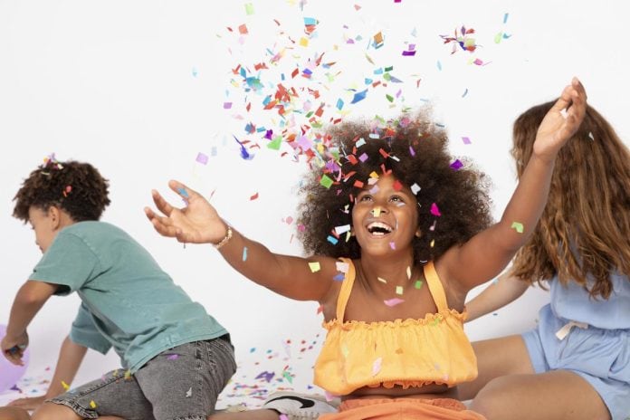 Três pré-adolescentes brincam com confetes de Carnaval