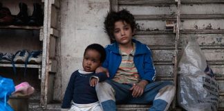 Imagem mostra dois garotos refugiados sentados lado a lado