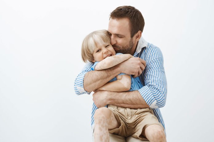 Pai abraça criança com vitiligo na infância