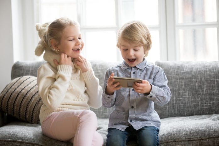 Crianças usando o celular, sorrindo e se divertindo