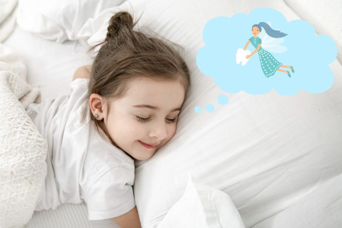 Menina dorme na cama e um fada do dente aparece em nuvem