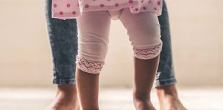 Criança com pernas arqueadas na infância andando pela casa
