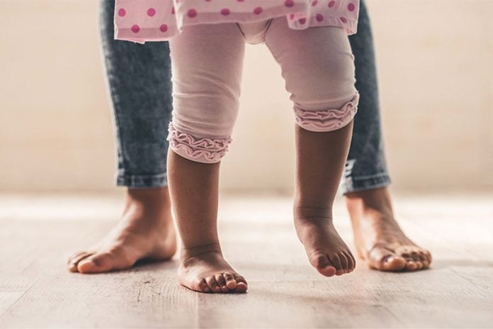 Criança com pernas arqueadas na infância andando pela casa