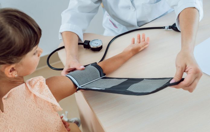 médica usando aparelho de pressão arteral no braço de criança
