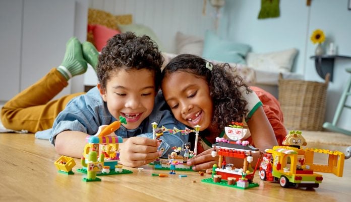 Menino e menina sorrindo, brincando de montar Lego