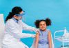 Menina de cabelo crespo preso nos lados recebe aplicação de vacina