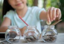 Menina põe moedas em três potinhos de vidro