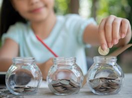 Menina põe moedas em três potinhos de vidro