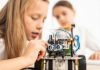 Menina ohando com cautela e interesse para um robô, que ela mesma está construindo
