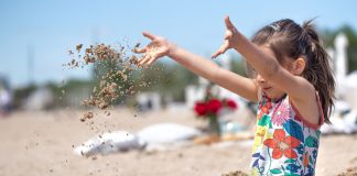 Criança na praia de maiô brincando com areia