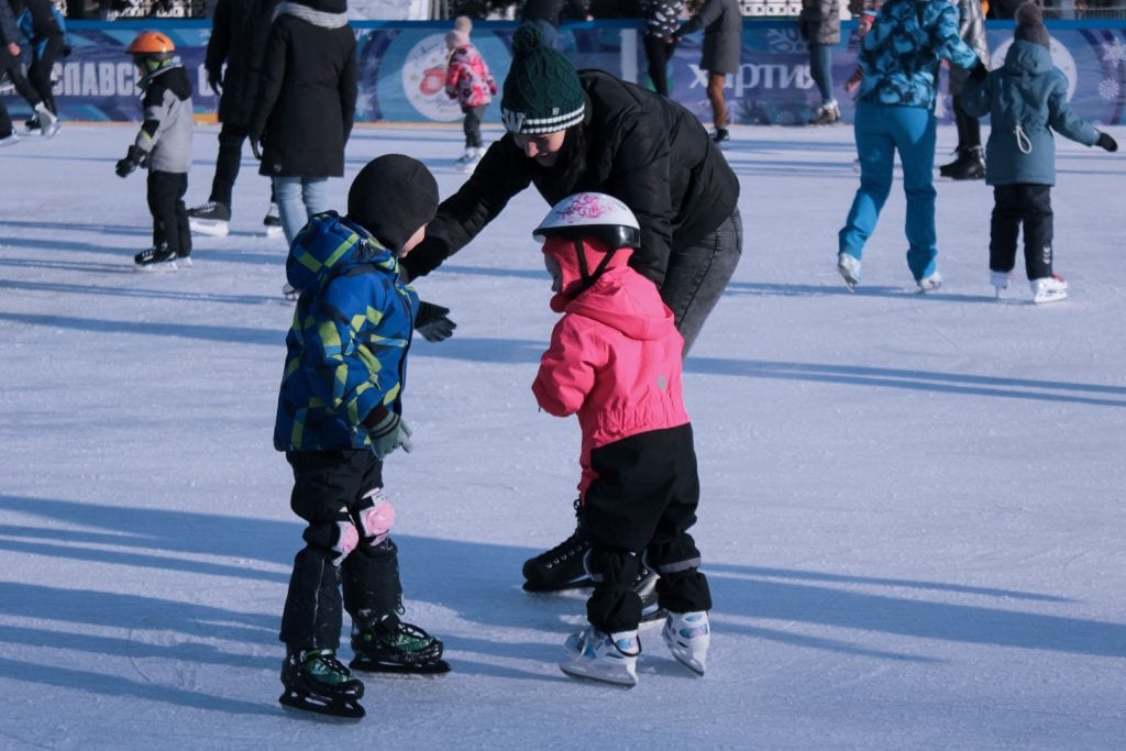 Duas crianças e sua mãe patinando juntas no gelo