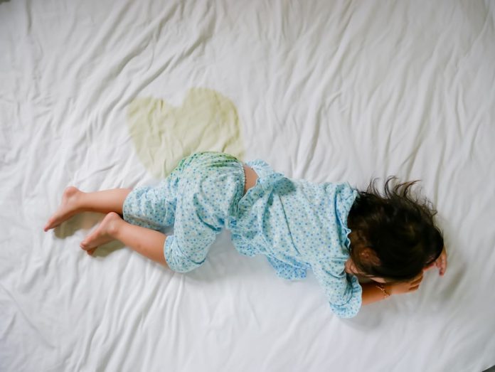 Criança dorme na cama com mancha de xixi