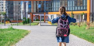 Menina de mochila caminha em direção à escola