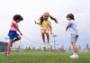 Três crianças brincam de pular corda no parque