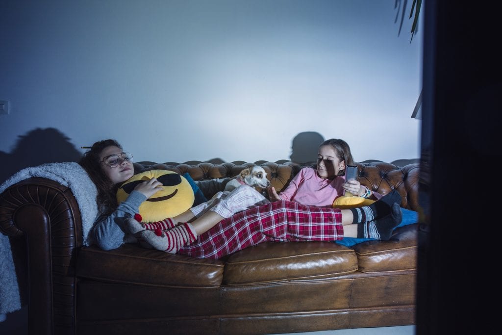 Duas crianças pequenas sentadas no sofá, assistindo televisão