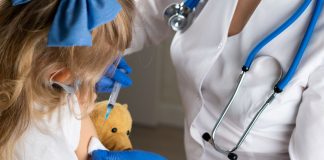 Criança com pelúcia recebe vacina no braço
