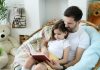 Pai e filha leem livro juntos sentados em poltrona