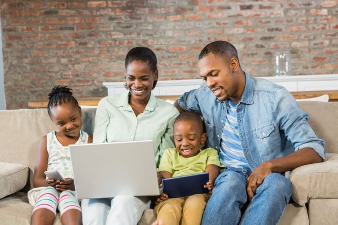 Mãe, pai e dois filhos leem no desktop sentados no sofá