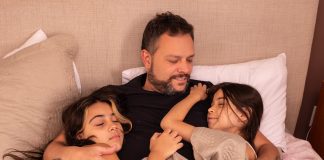Fernando Dias abraça as duas filhas na cama
